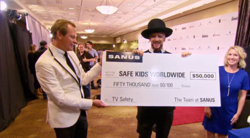 Boy George holding a check